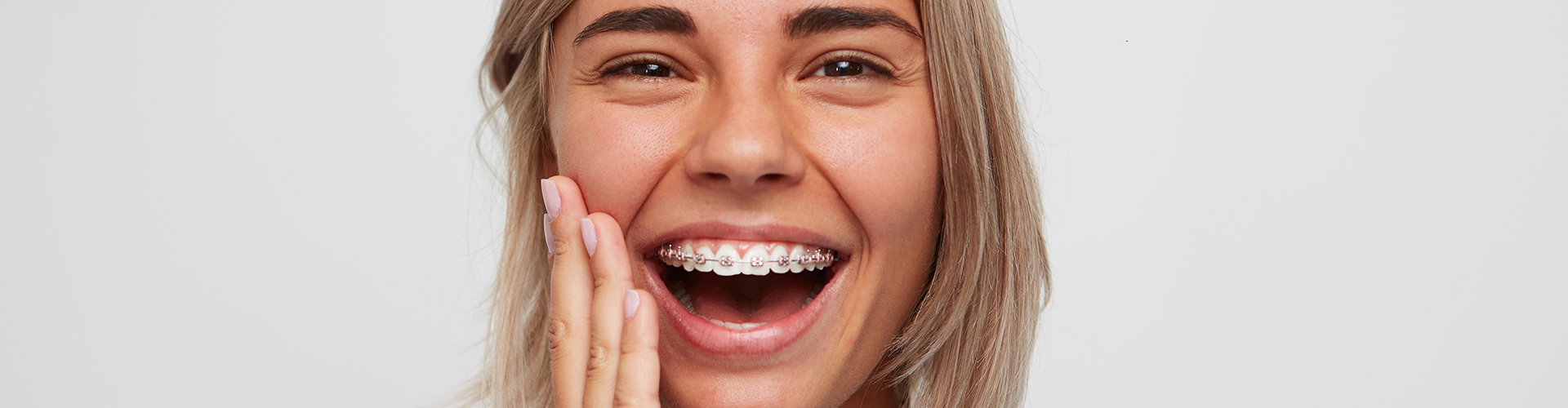 woman with braces holding hand on her cheek